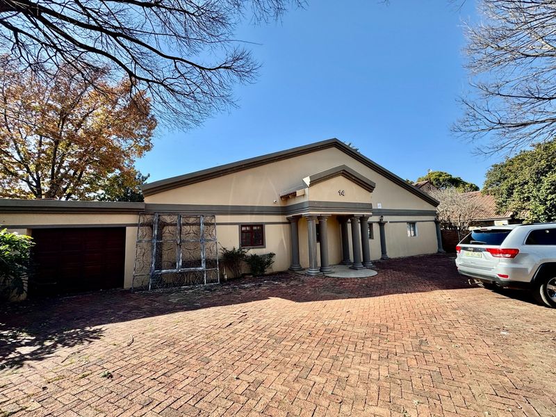 Front elevation of a house featuring a brick paved driveway, a garage, and a covered entrance porch with decorative columns.