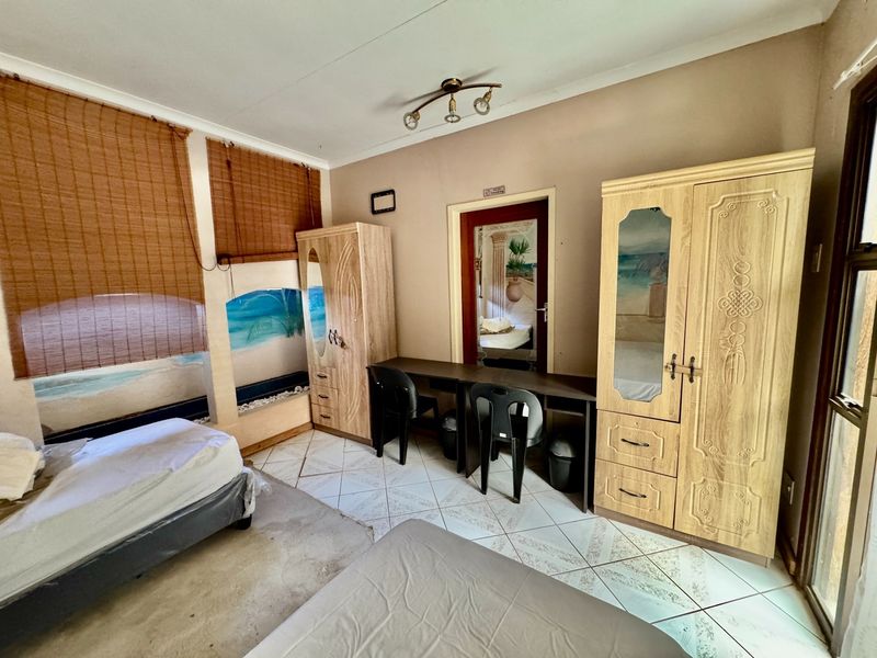 A bedroom featuring tiled flooring and built-in door frames, currently showing signs of wear and requiring cosmetic updates to improve its overall condition.