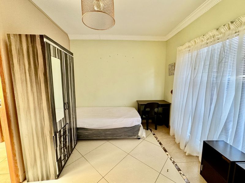 A bedroom featuring tiled flooring, decorative cornice, and window blinds, requiring minor wall repairs to restore the finish.