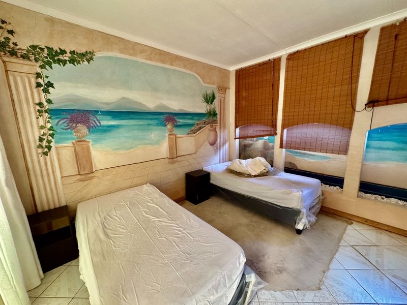 A bedroom featuring tiled flooring and a large decorative wall mural, requiring cosmetic updates to modernize the space.