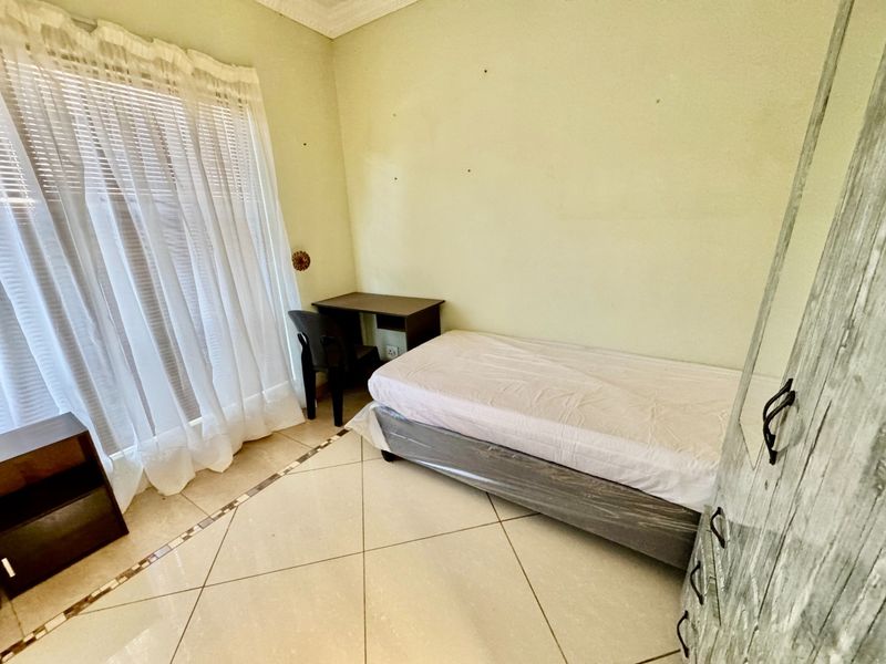 A functional bedroom featuring tiled flooring, neutral wall tones, and window blinds, offering a blank canvas for potential interior updates.