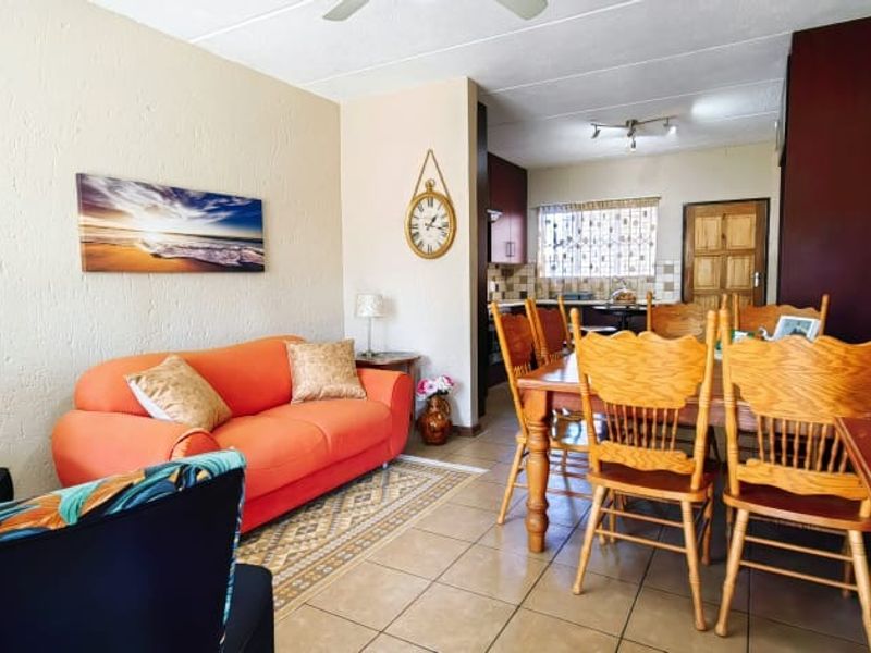 Open-plan living and dining area featuring tiled flooring, a ceiling fan, and a connected kitchen space with built-in cabinetry.