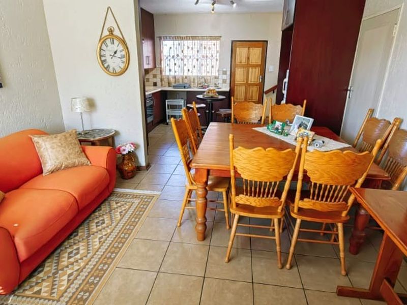 Open-plan living and dining area featuring tiled flooring, flowing into a functional kitchen with built-in cabinetry and appliances.