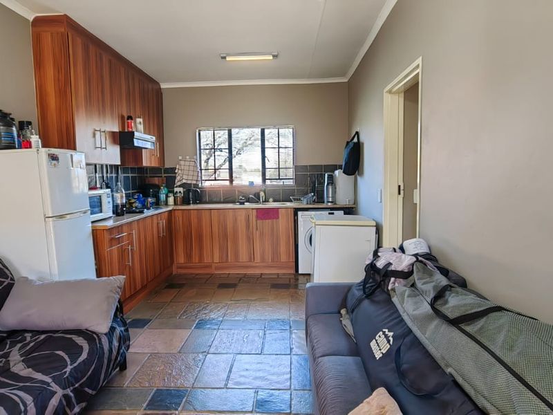 Open plan kitchen and living area featuring wooden cabinetry, tiled flooring, and functional workspace.