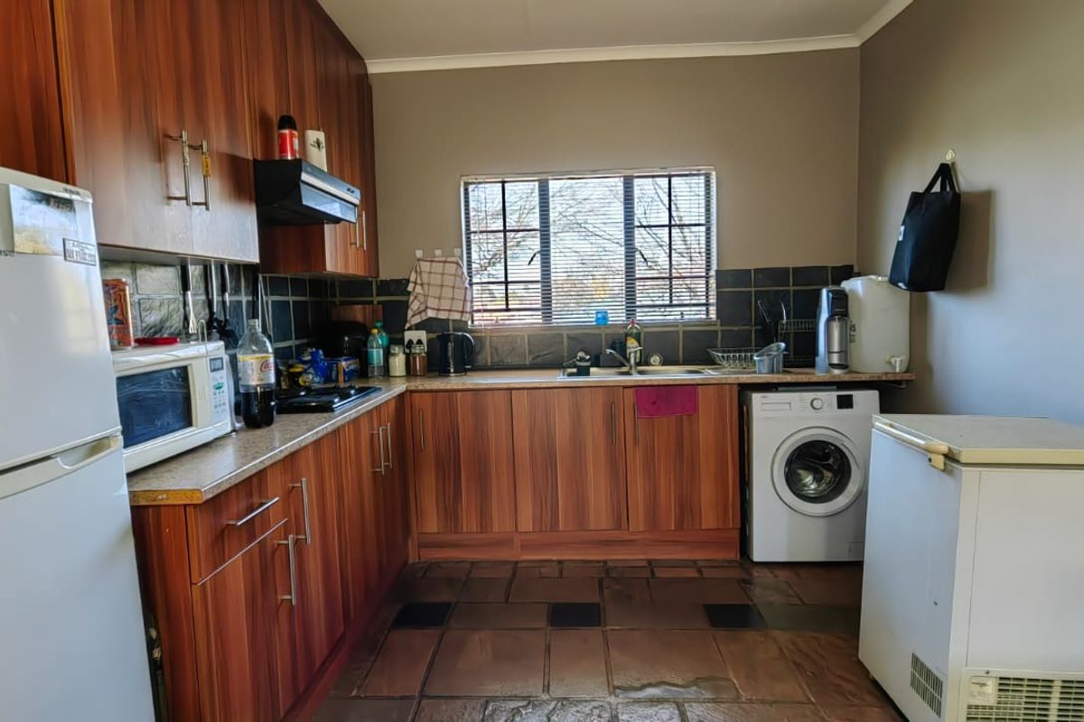 Functional kitchen featuring wood-look laminate cabinetry, tiled backsplash, and integrated sink area with space for laundry appliances.