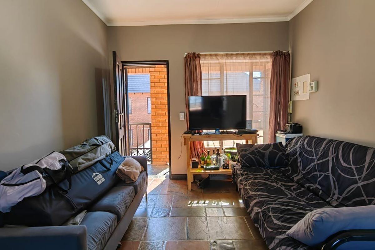 A living room featuring tiled flooring and direct access to an outdoor balcony area through a sliding door.
