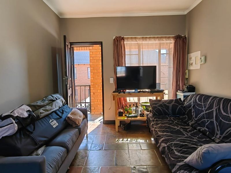 A living room featuring tiled flooring and direct access to an outdoor balcony area through a sliding door.