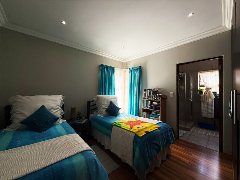 A well-maintained bedroom featuring laminate flooring, recessed downlighting, and direct access to an en-suite bathroom.