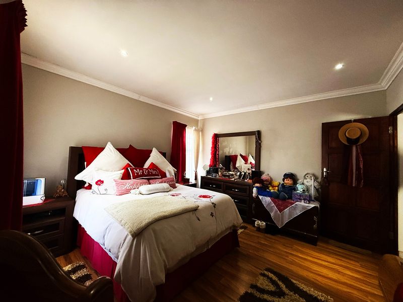 A well-maintained bedroom featuring timber flooring, recessed downlighting, and decorative cove cornicing, providing a comfortable and functional living space.
