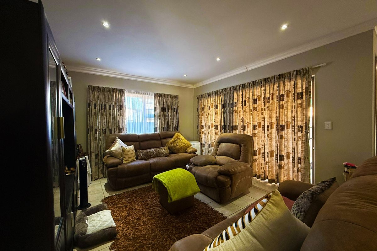 A comfortable living room featuring tiled flooring, recessed downlighting, and a sliding glass door providing access to the exterior.