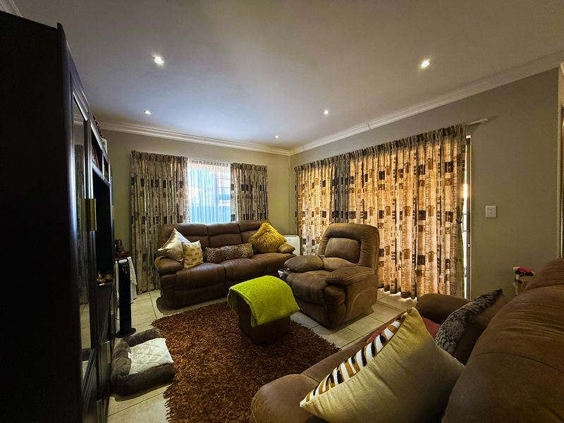 A comfortable living room featuring tiled flooring, recessed downlighting, and a sliding glass door providing access to the exterior.