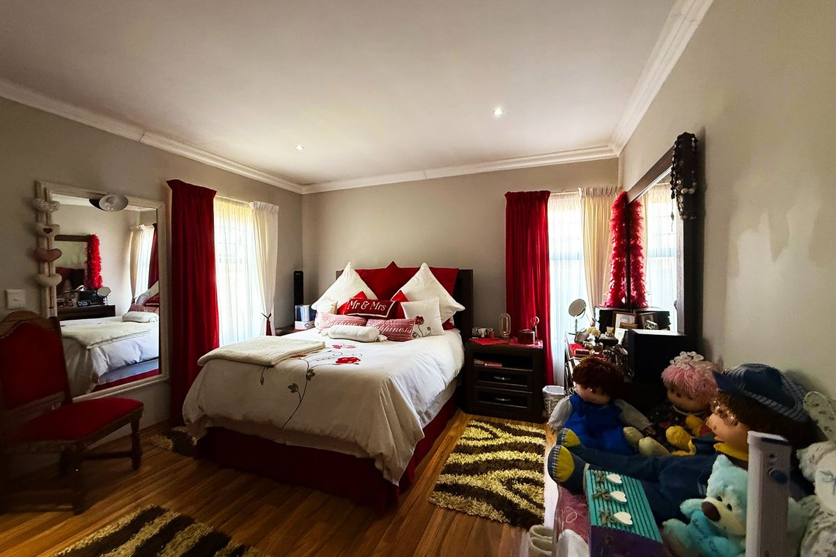A well-proportioned bedroom featuring laminate flooring, recessed downlighting, and decorative ceiling cornicing, offering a comfortable and functional living space.