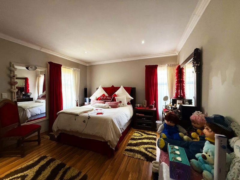 A well-proportioned bedroom featuring laminate flooring, recessed downlighting, and decorative ceiling cornicing, offering a comfortable and functional living space.
