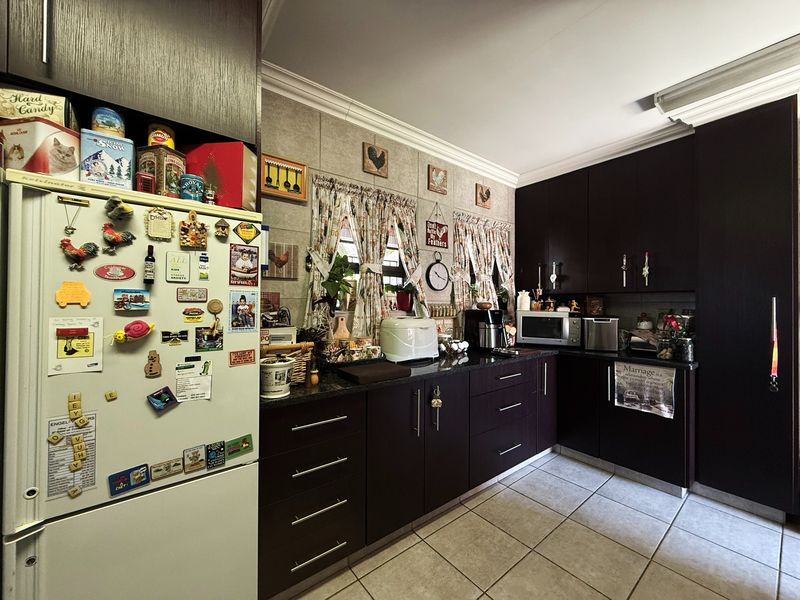 A functional kitchen featuring dark wood cabinetry, granite countertops, and tiled flooring, offering a classic layout with ample storage space.