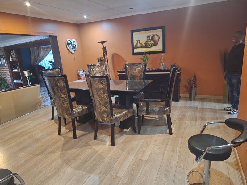 A dining room featuring light-toned laminate flooring and recessed ceiling lighting, providing a functional space for family meals.