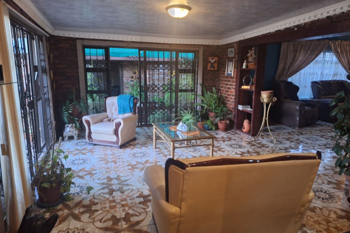 Spacious living area featuring exposed brick walls, decorative patterned floor tiles, and large sliding glass doors providing access to the outdoor space.