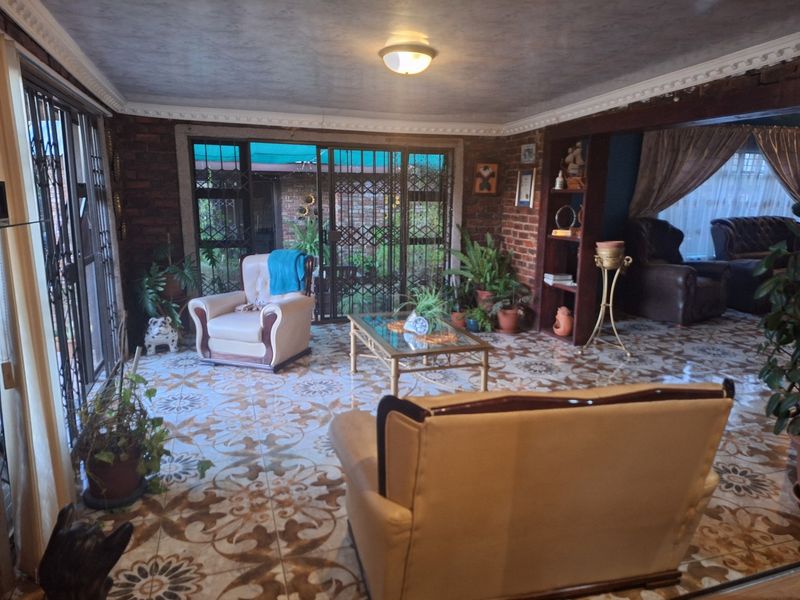 Spacious living area featuring exposed brick walls, decorative patterned floor tiles, and large sliding glass doors providing access to the outdoor space.
