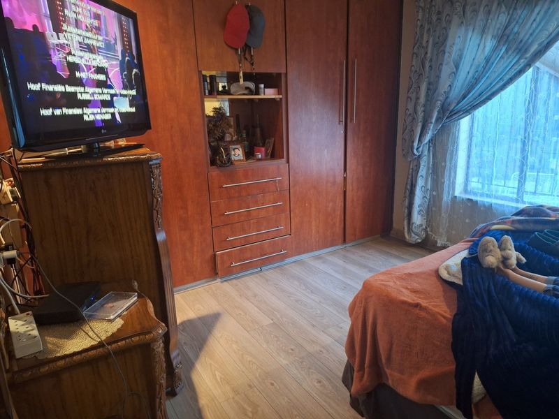 A bedroom featuring built-in wooden cupboards and laminate flooring, providing functional storage and a neutral base for the room.