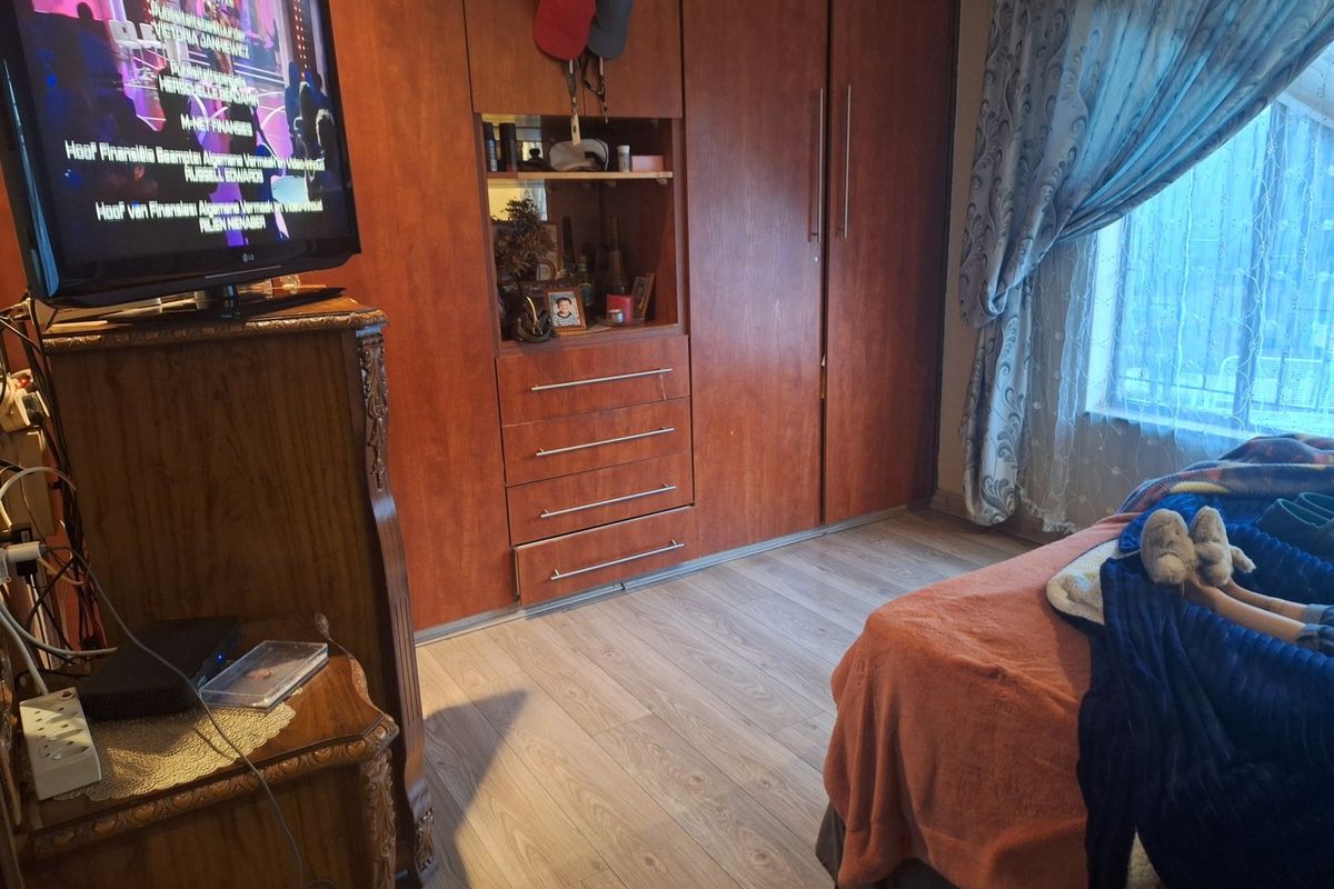 A bedroom featuring built-in wooden cupboards and laminate flooring, providing functional storage and a neutral base for the room.