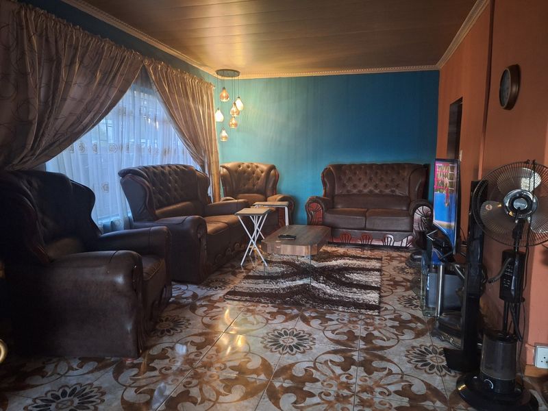 A living room featuring decorative patterned floor tiles, coved ceiling details, and modern pendant lighting, offering a functional space for relaxation.