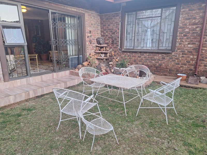 Rear exterior view featuring a face brick facade, tiled patio area, and a stone water feature with access to the interior via sliding doors.