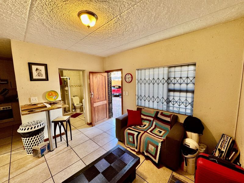 Open plan living area featuring tiled flooring, a built-in breakfast bar, and direct access to an adjoining bathroom and exterior entrance.