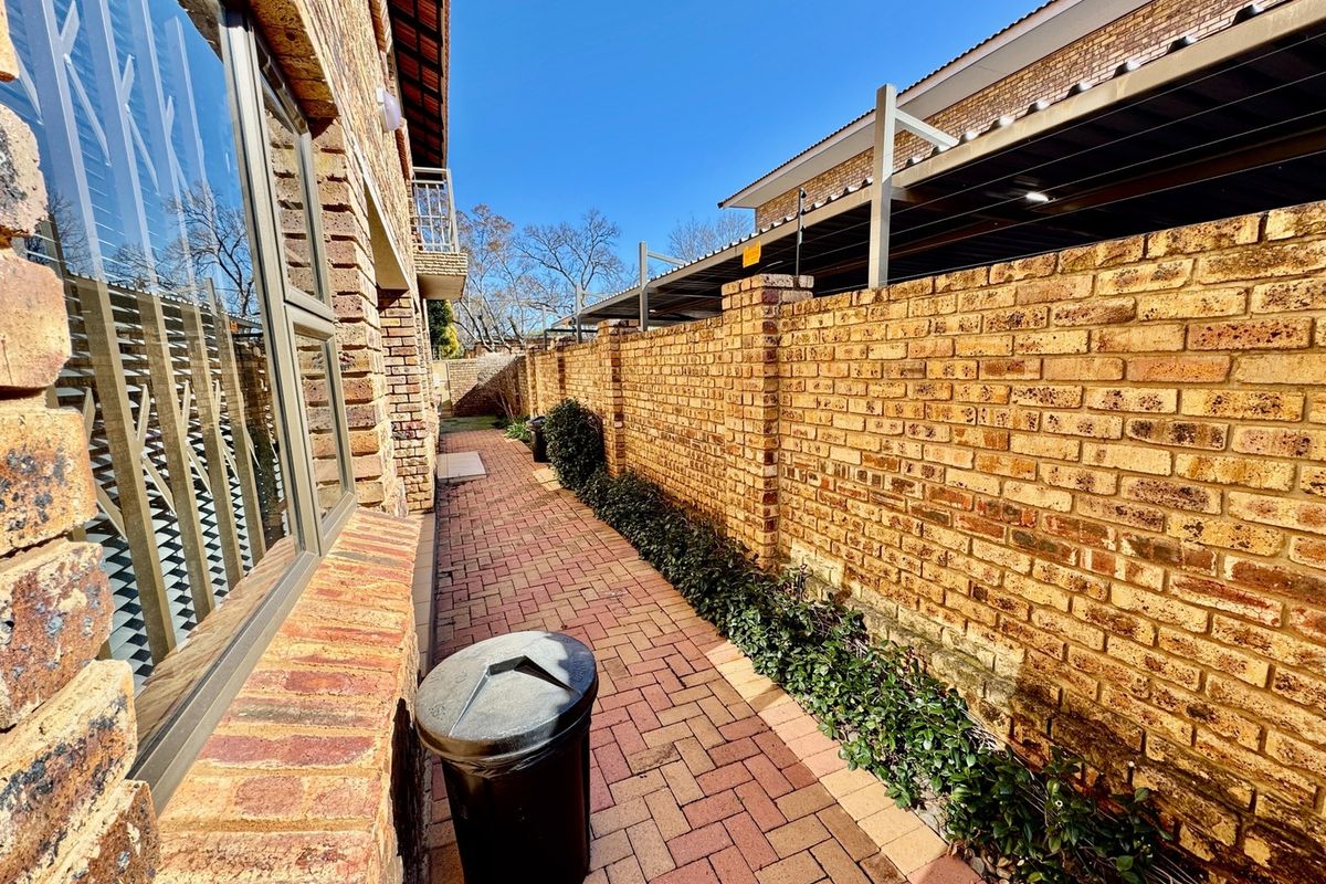 A side walkway featuring face brick boundary walls and paved flooring, leading towards the rear of the apartment complex.