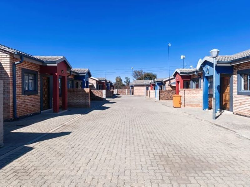 A view of the complex driveway featuring face brick apartment units with pitched tiled roofs and paved access paths.