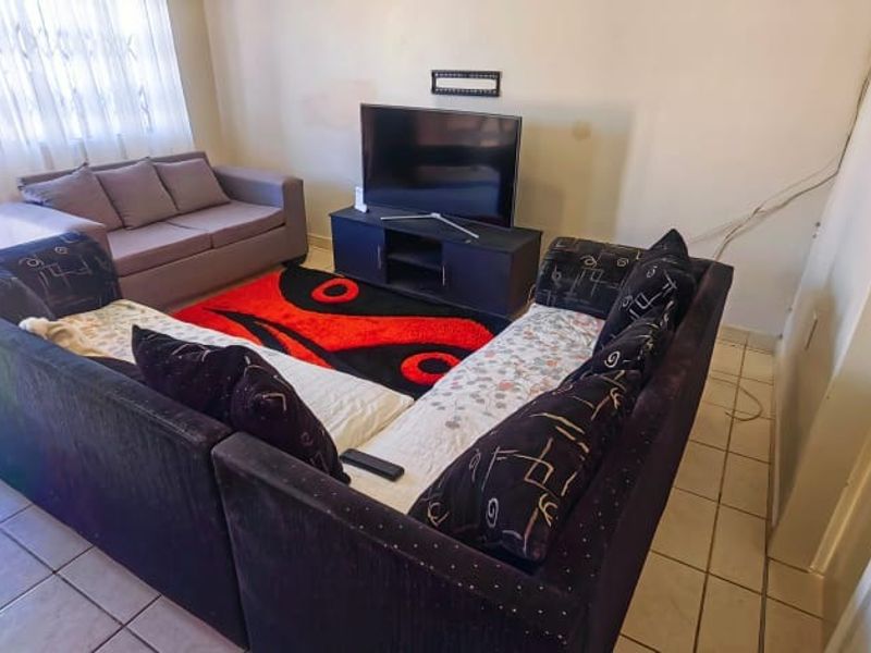 A living room area featuring tiled flooring and access to an outdoor space via a sliding door.