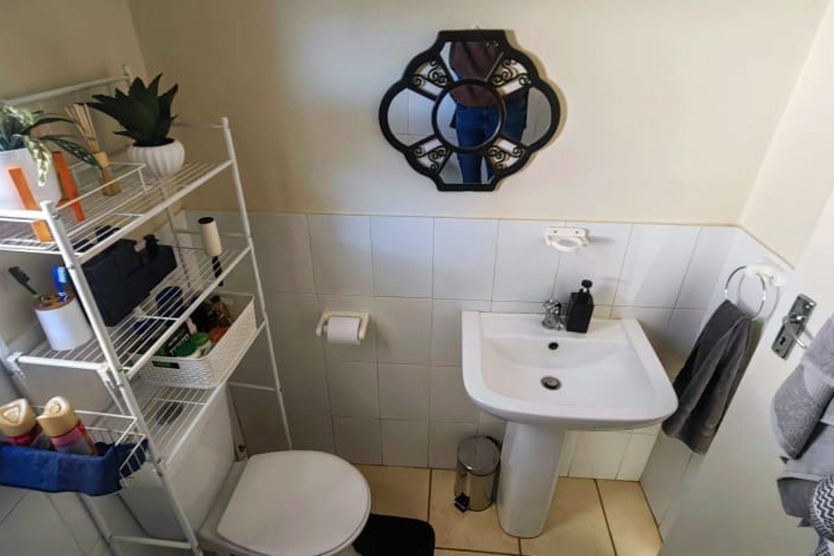A compact bathroom featuring a pedestal basin, tiled walls, and standard toilet fixtures.