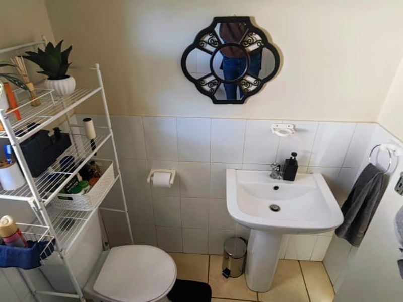 A compact bathroom featuring a pedestal basin, tiled walls, and standard toilet fixtures.