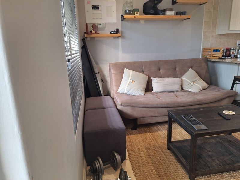 Open plan living area featuring tiled flooring, venetian blinds, and wall-mounted shelving units, providing a functional space adjacent to the kitchen area.
