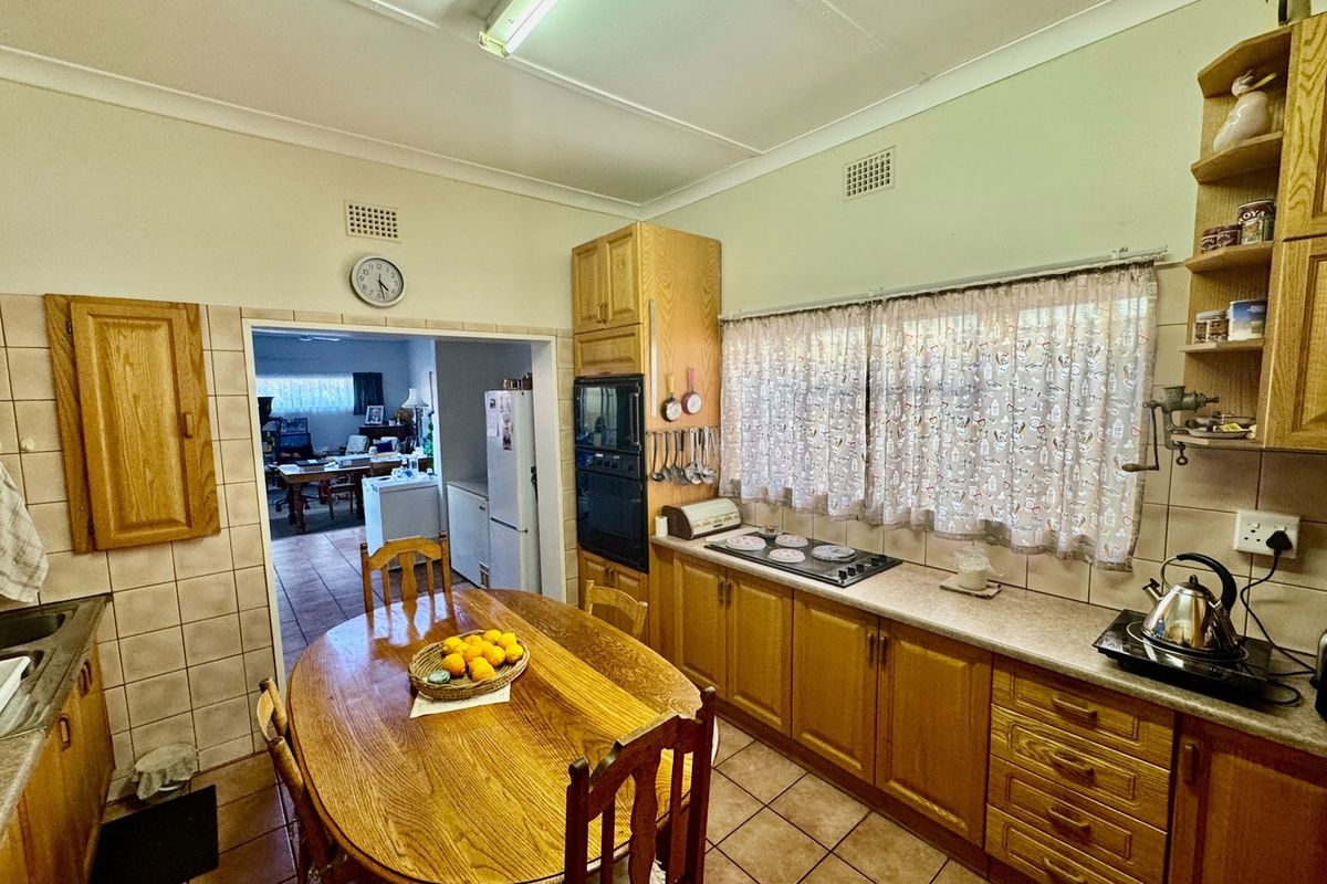 A functional kitchen featuring traditional timber cabinetry, laminate countertops, built-in oven, and tiled flooring, offering a classic layout with potential for modern updates.