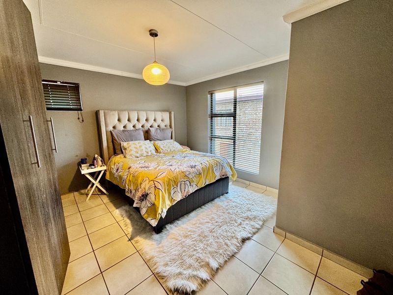 A well-maintained bedroom featuring tiled flooring, built-in wardrobe storage, and venetian blinds, providing a functional and comfortable living space.