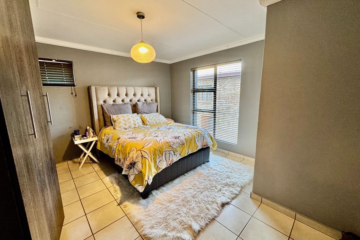 A well-maintained bedroom featuring tiled flooring, built-in wardrobe storage, and venetian blinds, providing a functional and comfortable living space.