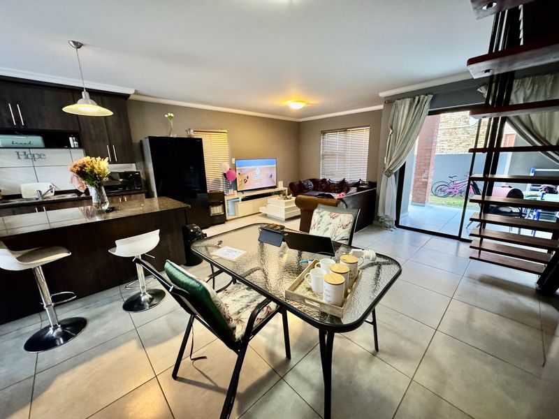 Open-plan living area featuring a modern kitchen with dark cabinetry, granite countertops, tiled flooring, and direct access to an outdoor patio via sliding doors.