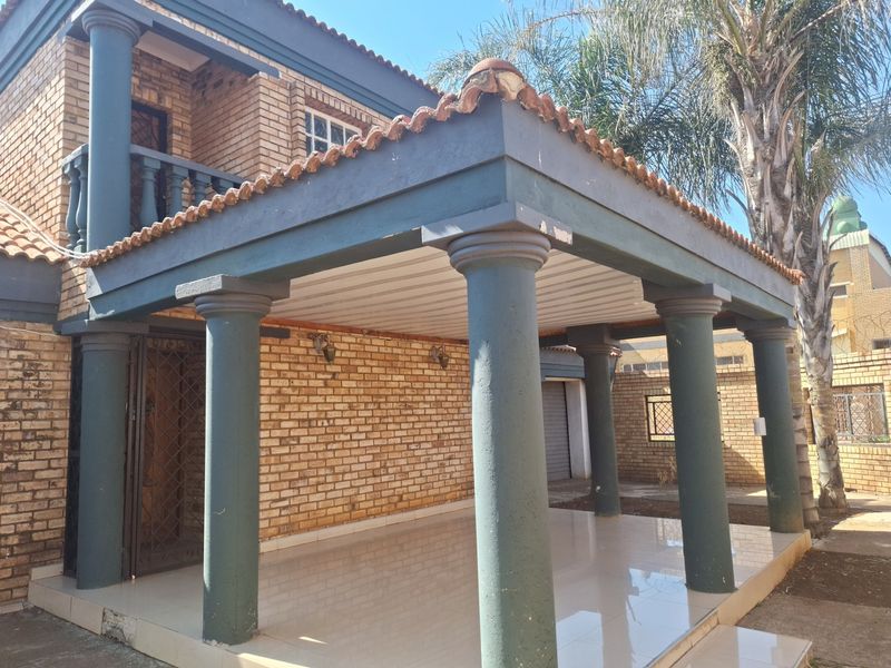 A covered patio area featuring tiled flooring, brick wall finishes, and decorative columns, providing a sheltered outdoor space.
