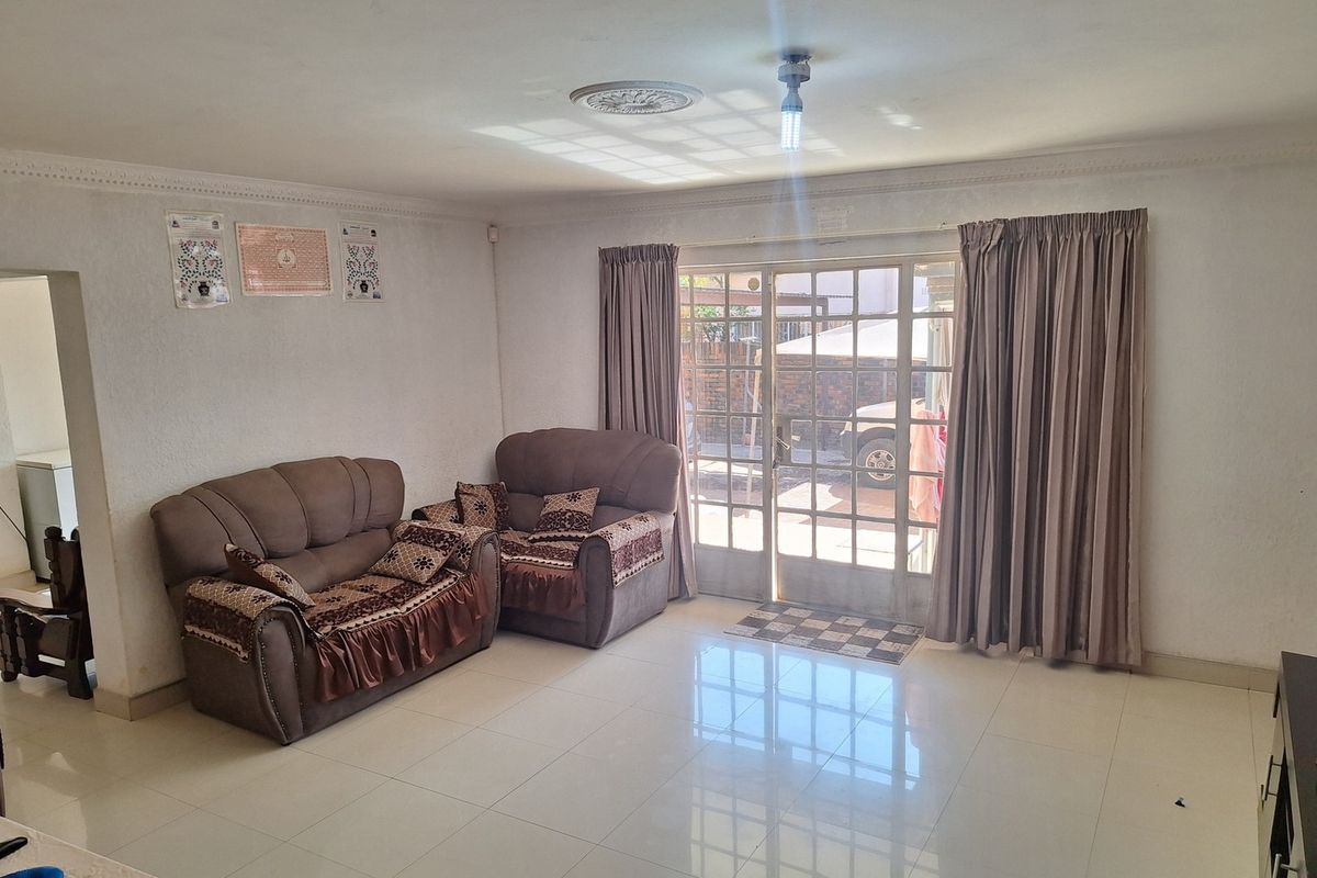 A bright living room featuring tiled flooring, decorative ceiling cornice, and a sliding glass door providing access to the exterior.