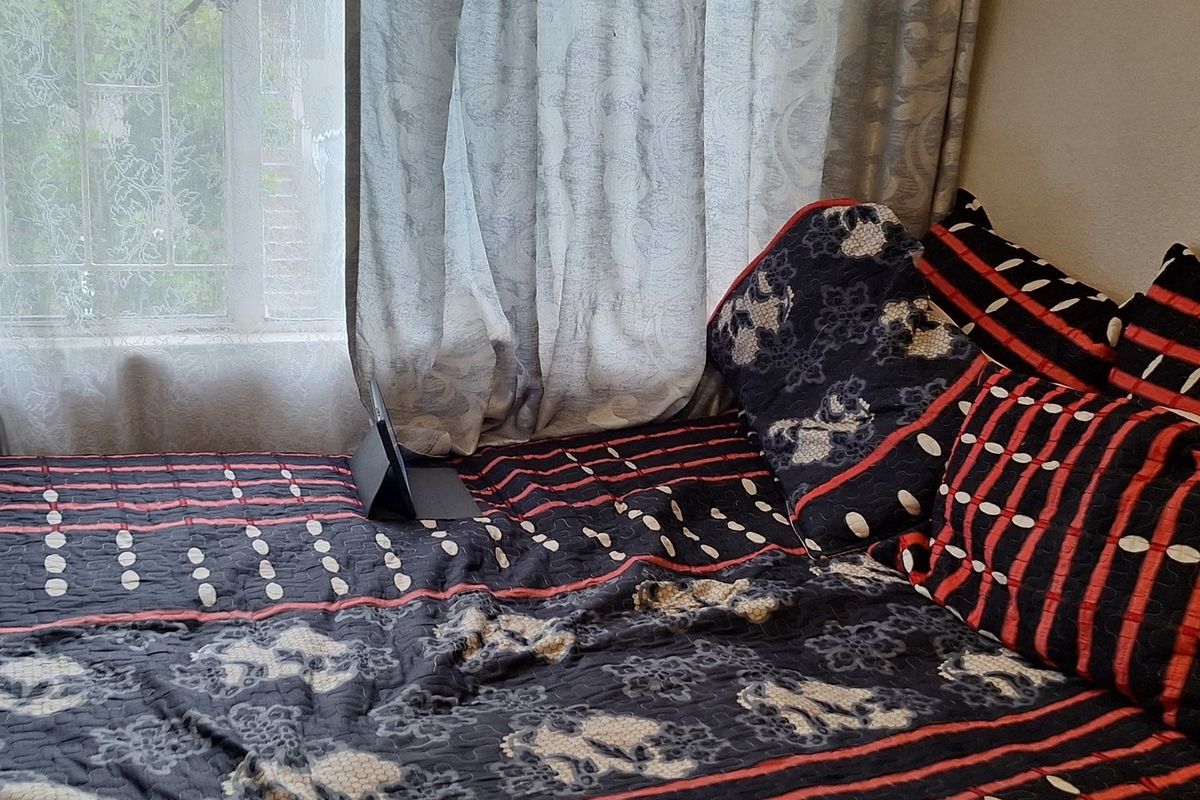 A bedroom interior featuring a window with security bars and curtains.