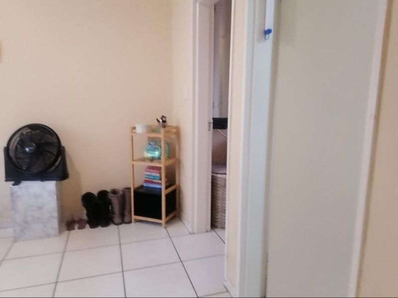 A simple hallway area featuring neutral wall finishes and tiled flooring, providing access to adjacent rooms within the apartment.