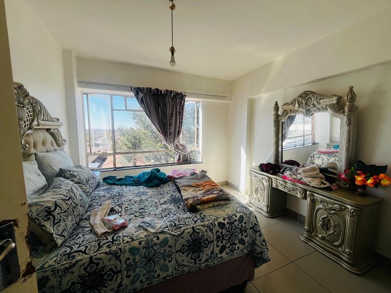 A bedroom featuring tiled flooring and a large window providing natural light and an exterior view.