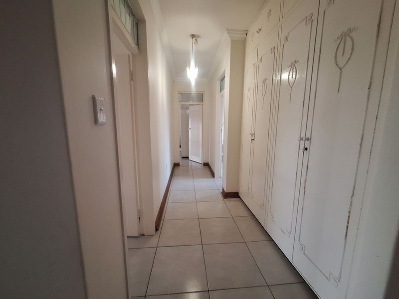 A long hallway featuring tiled flooring and extensive built-in storage cupboards with decorative detailing.