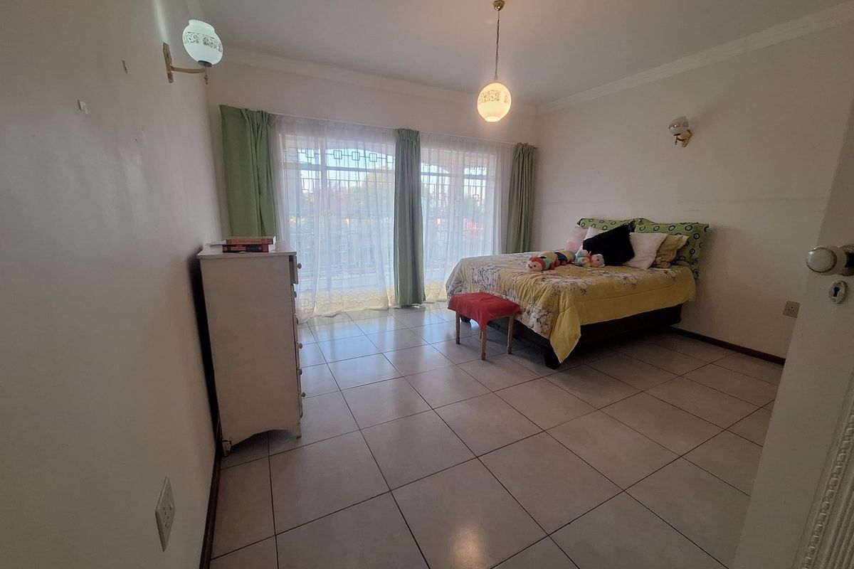 Spacious bedroom featuring tiled flooring, sliding glass doors leading to an outdoor area, and classic wall-mounted lighting fixtures.