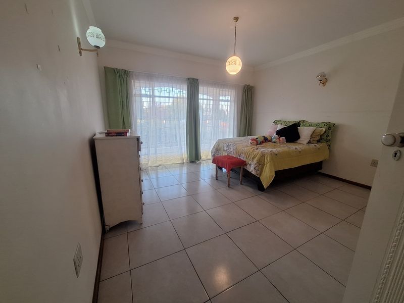 Spacious bedroom featuring tiled flooring, sliding glass doors leading to an outdoor area, and classic wall-mounted lighting fixtures.