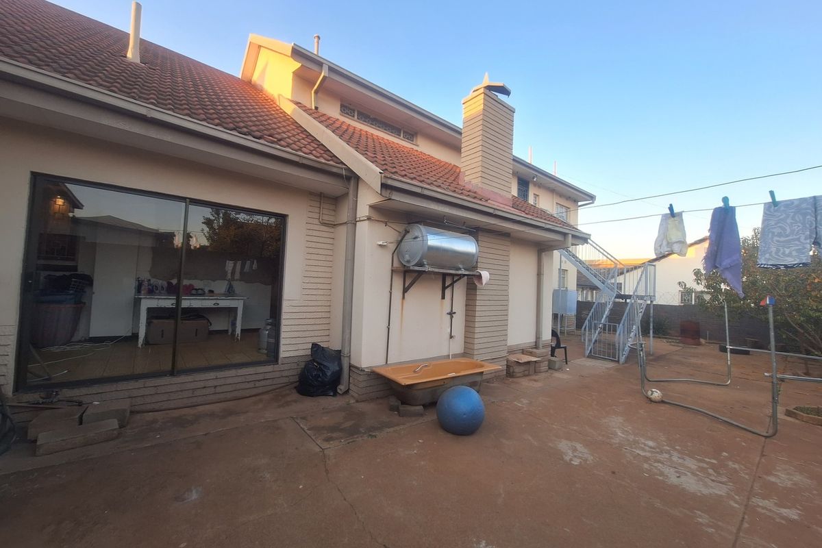 Rear exterior view of the house featuring a tiled roof, solar water heater, and an external metal staircase leading to the upper level.