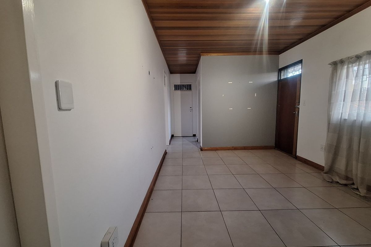 An empty living area featuring tiled flooring and a timber ceiling, providing a neutral blank canvas for interior design.