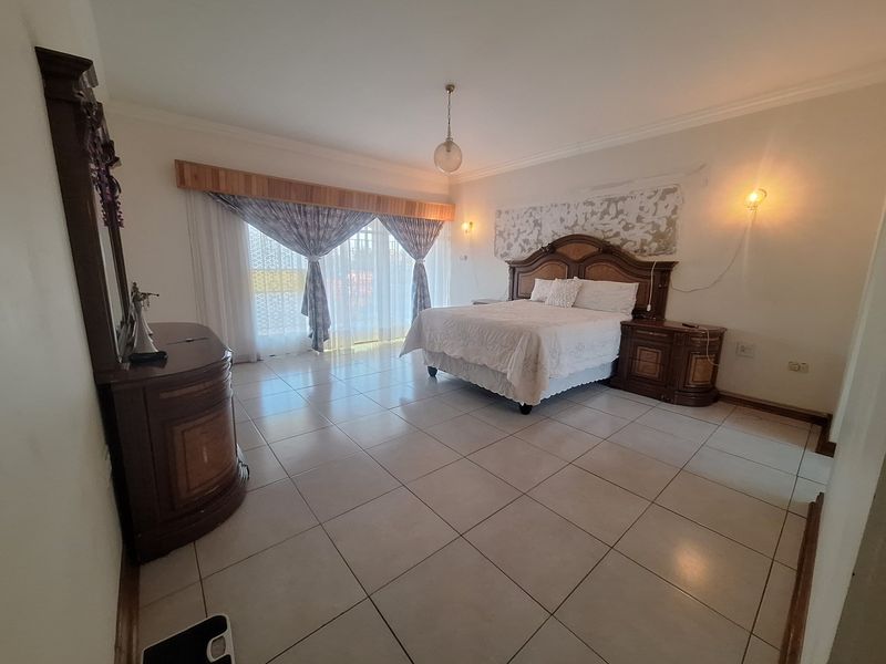 Spacious bedroom featuring neutral tiled flooring, cove cornicing, and large sliding glass doors providing natural light.