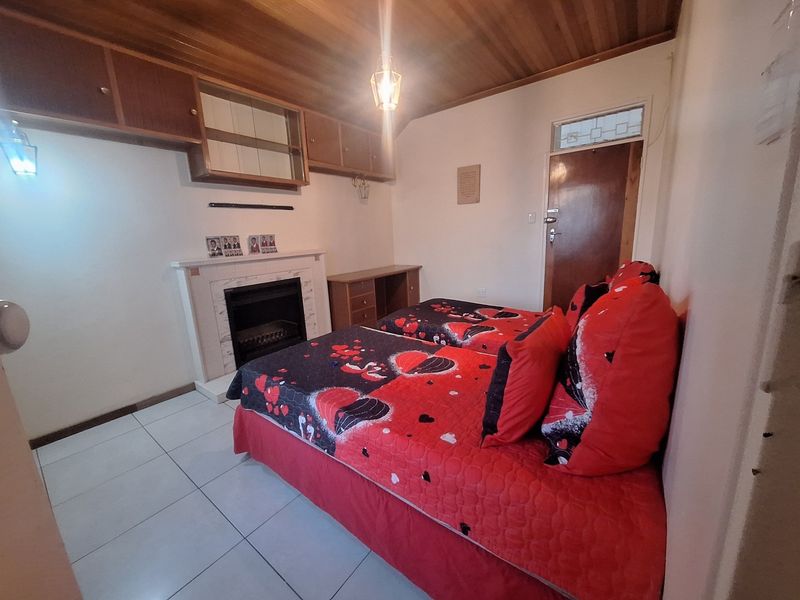 A bedroom featuring a built-in fireplace, overhead cabinetry, tiled flooring, and a timber-clad ceiling.