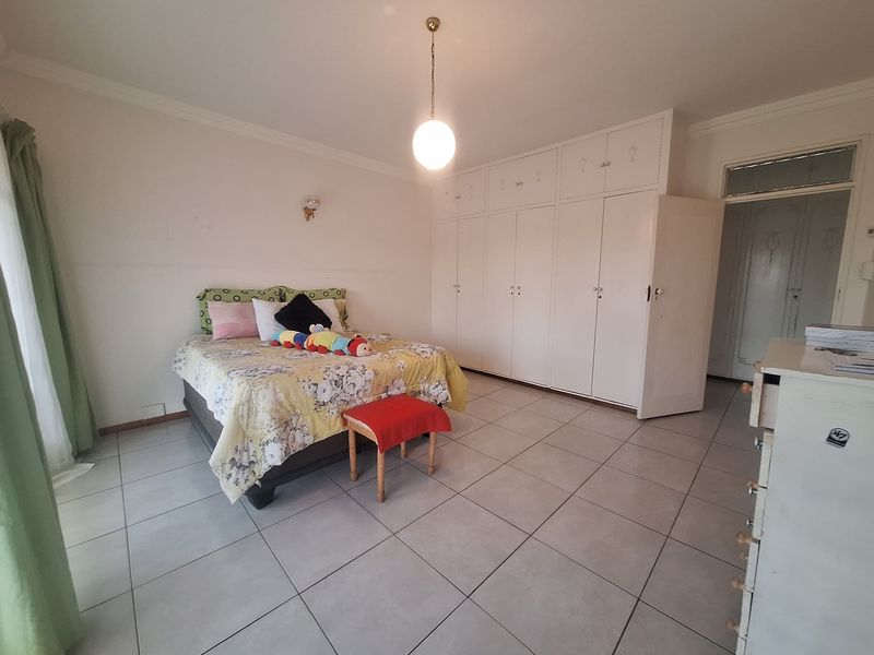 Spacious bedroom featuring neutral tiled flooring, extensive built-in cupboard storage, and classic cove cornice detailing.