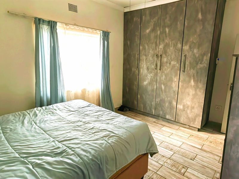 A bedroom featuring tiled flooring and floor-to-ceiling built-in cupboards with a textured finish.